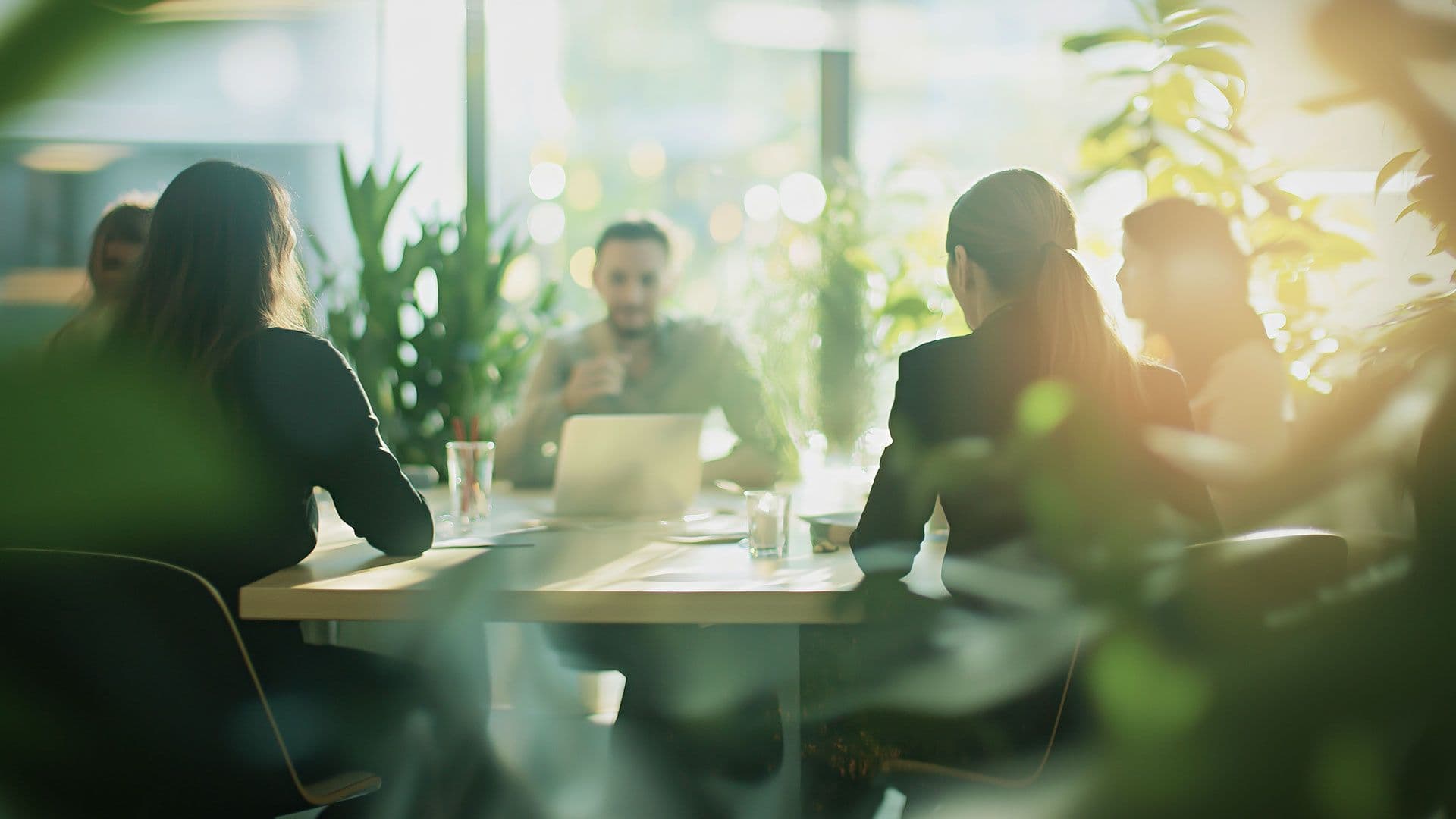 Business people having a meeting in an office full of plants.